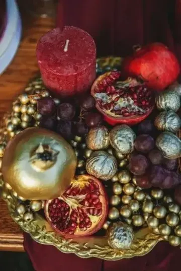 Altın kaplama meyveler, narlar ve kırmızı mumla zarif sonbahar masa süsü.