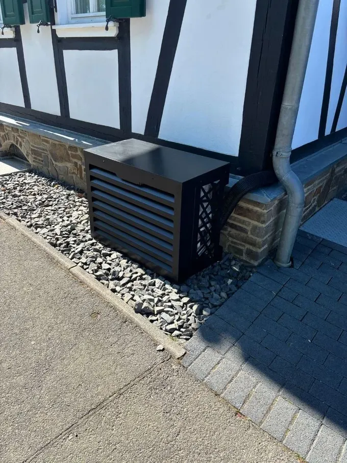 Bu küçük siyah metal kutu cepheyle uyumlu ve klima ünitesini tamamen koruyor.