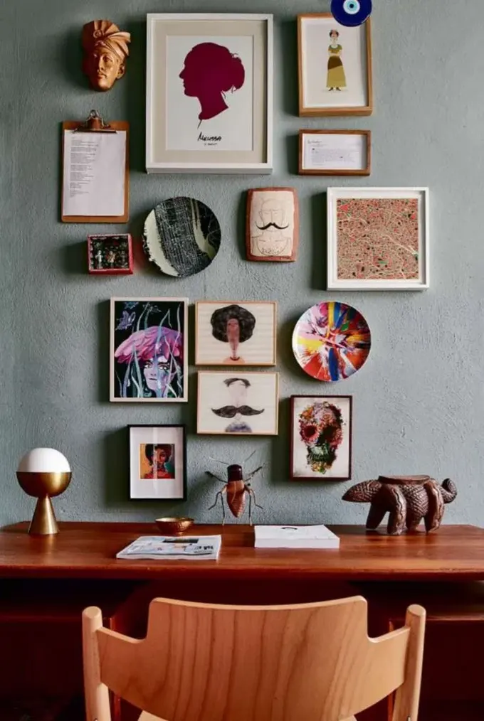 Bu canlı galeri duvarı küçük sanat eserleri ve posterlerle çalışma alanını serin gösteriyor.