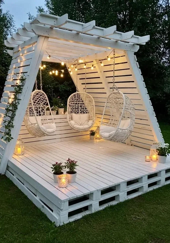 Üç yumurta şekilli sandalye ve ışıklarla tasarlanmış benzersiz beyaz pergola, gerçek bir bahçe köşesi.
