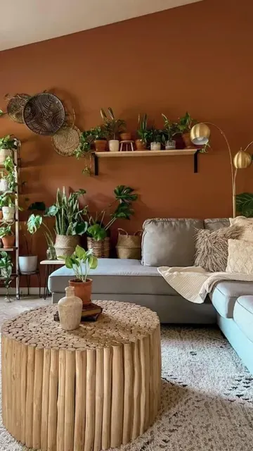 Modern bohem oturma odası; terrakota vurgu duvarı, yeşil kanepe, saksı bitkileri ve altın dokunuşlarla şık bir ortam yaratılmış.