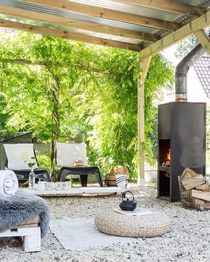 Trapez metal çatılı pergola, gerçek güneş koruması için iyi bir fikir; yan taraflar yeşil sarmaşıklarla kaplı.