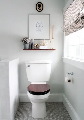 Küçük nötr tonlarda banyo, yarım duvar ile tuvaleti diğer alandan ayırıyor.