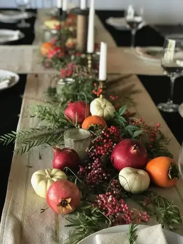 Narlar, balkabakları, meyveler, yeşillikler ve mumlarla cesur ve dikkat çekici sonbahar masa dekoru.