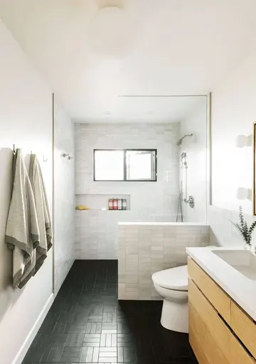 Mermer ince fayanslar ve siyah zeminli modern banyo, ahşap asma lavabo, yerleşik saklama nişi.