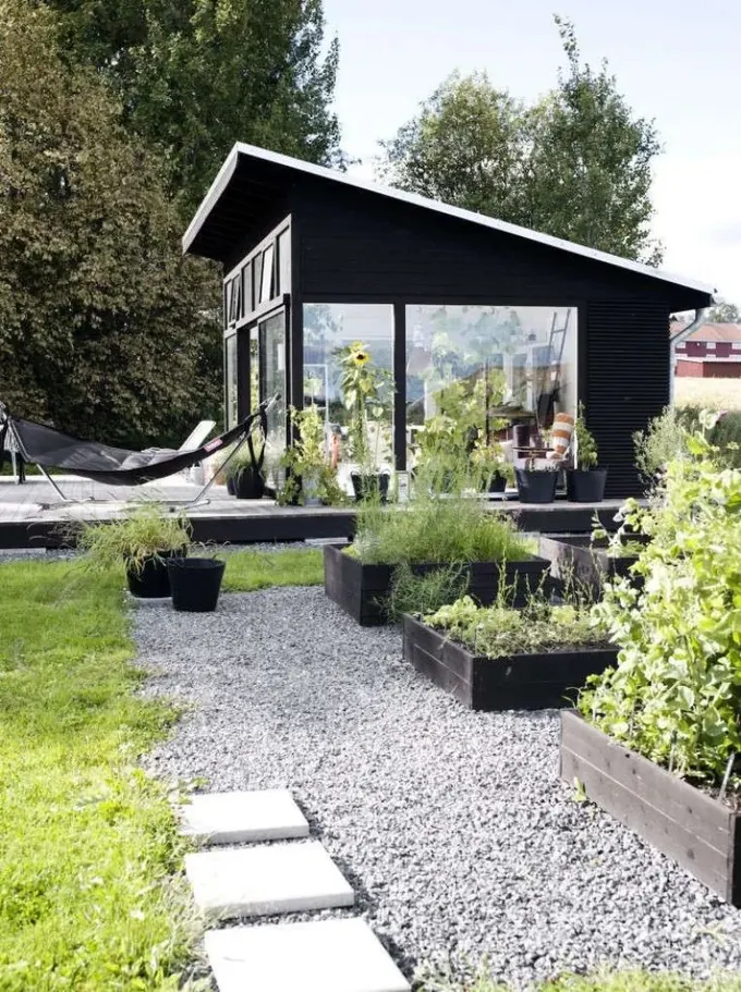 İskandinav tarzı siyah bahçe evi, hamak ve bahçe yatakları ile tasarlanmış alan.