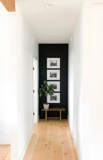 Uzun koridordaki siyah vurgu duvarda küçük bir sanat galerisiyle alana hareket kazandırılmış.