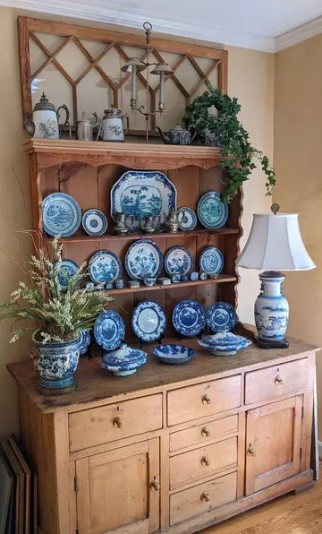 Boyalı büfedeki vintage mavi tabaklar, uyumlu lambalar ve saksılarla birlikte öne çıkıyor.