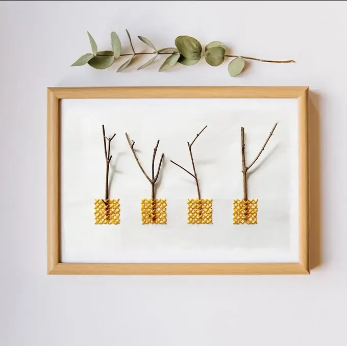 Küçük çerçevelerde düzenlenmiş dallardan oluşan minimal sanat eseri, zarif ve doğal bir dokunuş sağlıyor.