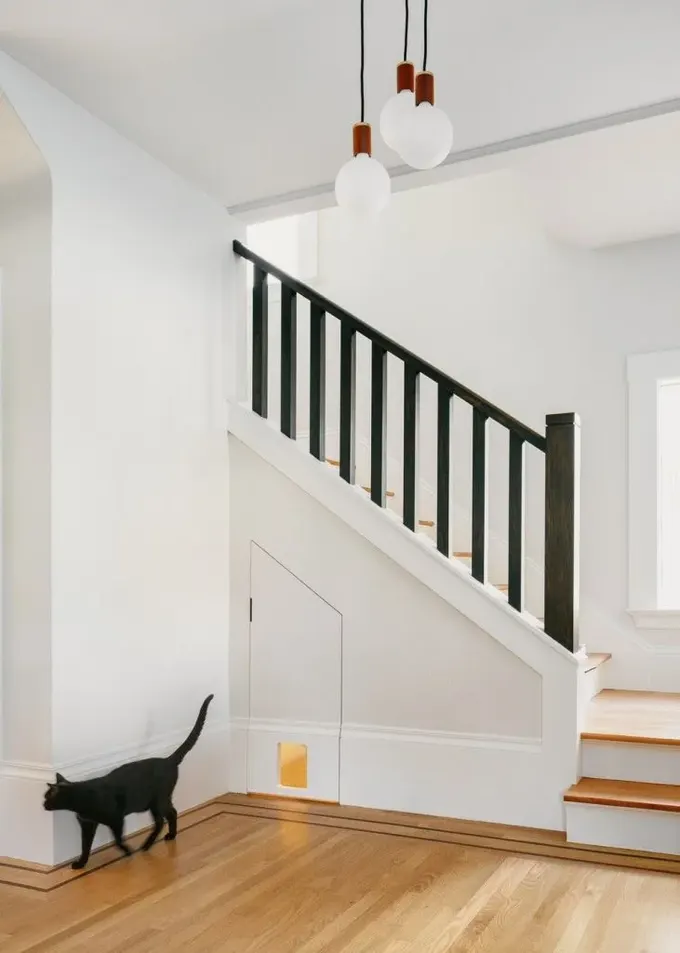 Kedi kumu kutusu merdiven altında gizlenmiş, küçük kapı kedinin rahat girmesini sağlıyor.