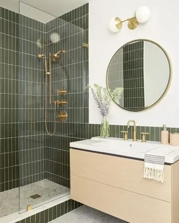 Yeşil ince fayanslar, asma lavabo, yuvarlak ayna, altın ve pirinç armatürlü modern banyo.