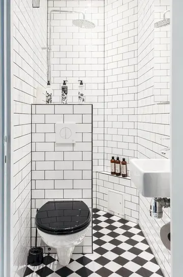 Retro esintili siyah beyaz banyo, duş alanı, mozaik döşeme ve yarım duvar ile şık.
