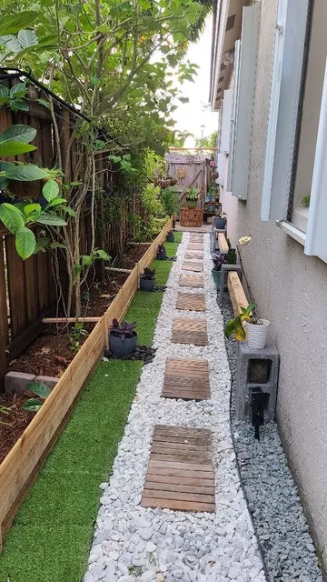 Dar yan bahçe ince bitkiler ve çimle düzenlenmiş. Yol, çakıl ve ahşap basamaklardan oluşuyor.