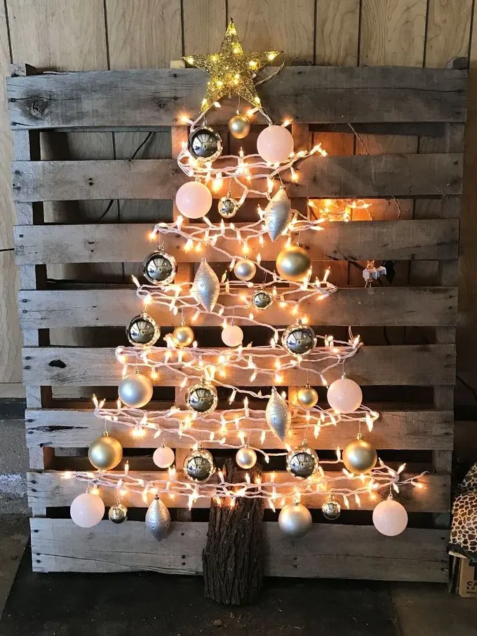 Palet, üzeri Noel ışıkları, gümüş ve beyaz süslerle dekore edilmiş bir Noel ağacı için arka plan oluşturuyor.