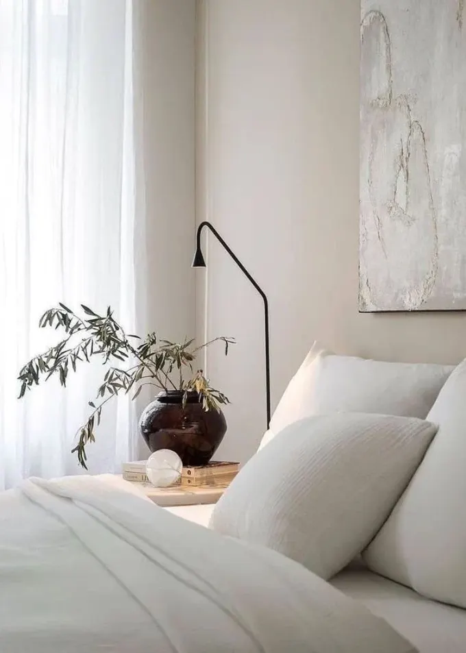 Saksı bitkisi ve dokulu nevresim takımı, sakin minimalist yatak odasını daha dikkat çekici yapar.