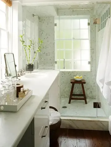 Sıcak küçük banyo; büyük lavabo, gömme lavabo, koyu renkli zemin ve açık yeşil duş alanı.