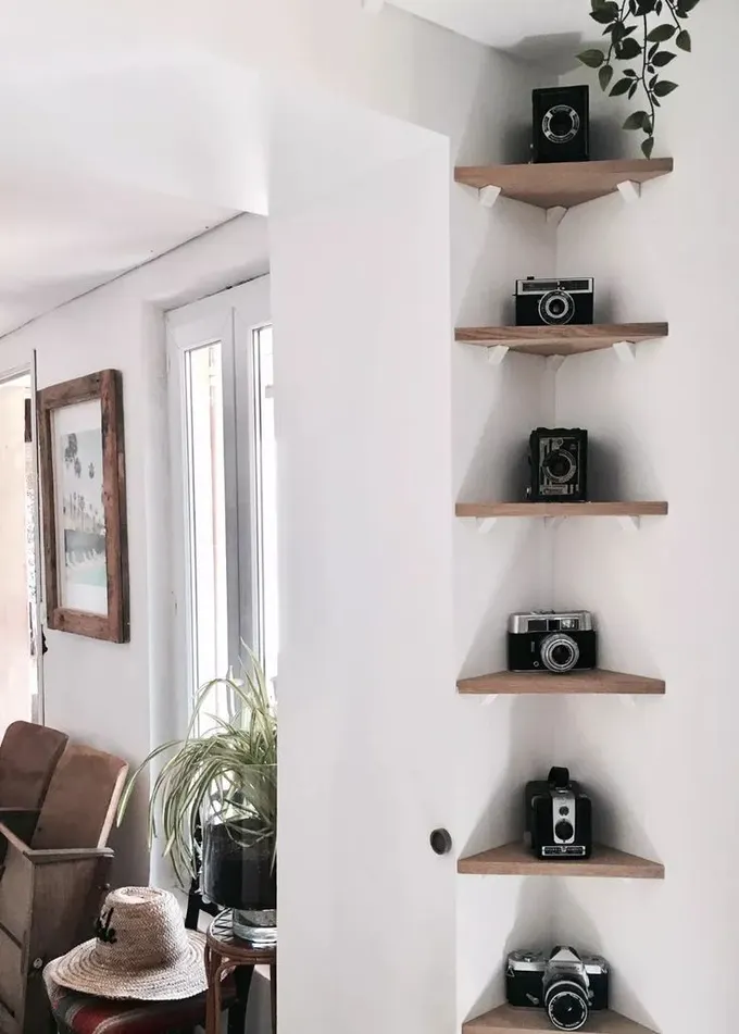 Küçük köşe raflarından oluşan köşe galerisi duvarında vintage kameralar sergileniyor.
