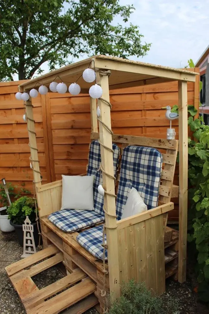 Küçük ve rahat bu pergola, paletler ve standart ağaçtan yapıldı, baskılı minderler ve yastıklar ile üzeri ışıklarla dekore edildi.