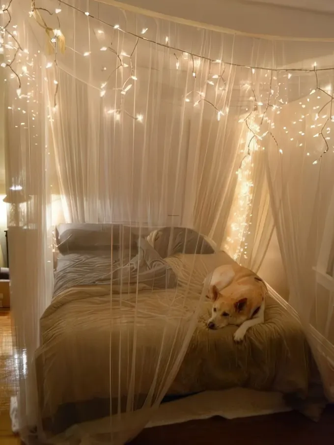 Taupe nevresimlerle alçak yatağı ve ışıklı yarı şeffaf tavan süsüyle nötr ve hoş bir yatak odası tasarımı.
