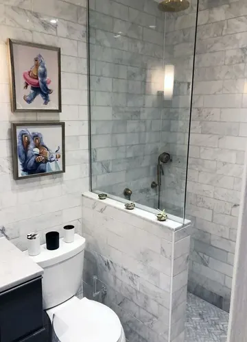 Küçük nötr banyo, mermer fayanslar, yarım duvarlı duş, küçük eğlenceli galeri duvarı.