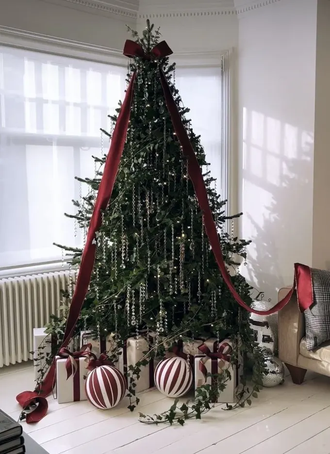 Modern yılbaşı ağacı vintage buz sarkıtları, büyük kırmızı fiyonk ve alt kısımda yeşilliklerle gösterişli.