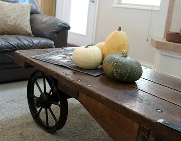 Üç doğal balkabağına sahip açık kahve masası; rustik ve cool sonbahar ev dekoru.
