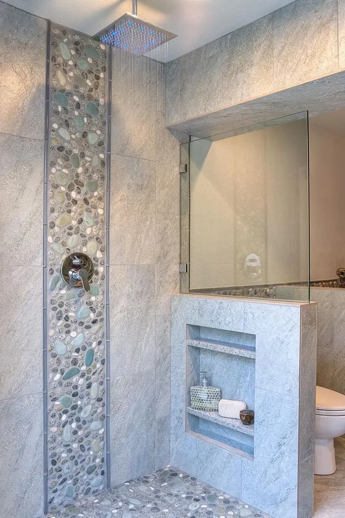 Seramik ve yapay çakıl taşlarıyla kaplanmış, raflı pencere pervazı bulunan hoş ve nötr bir banyo.