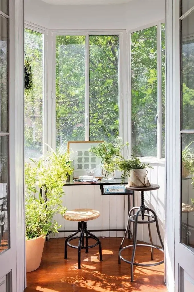 Bu küçük kapalı balkon, yeşillikler ve çiçeklerle mini bir çalışma alanına dönüşmüş.