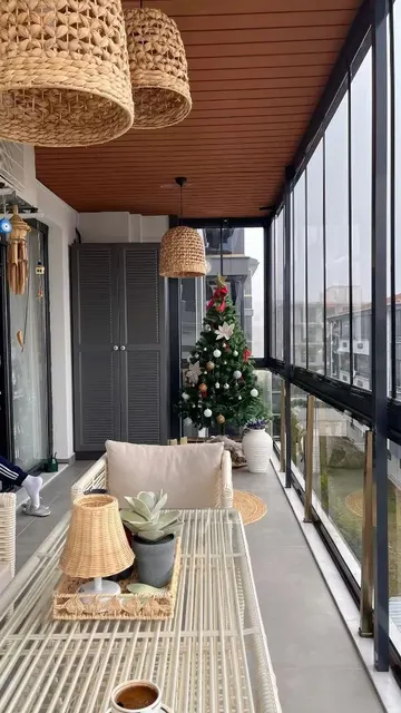 Uzun oturma odasında depolama alanı, dekor ve beyaz hasır mobilyalar yer alıyor.