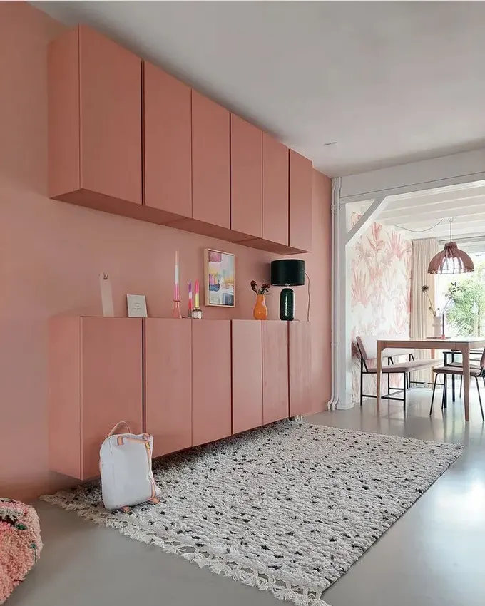 Toz pembe vurgu duvar, aynı renkte bir depolama ünitesiyle tamamlanmış.