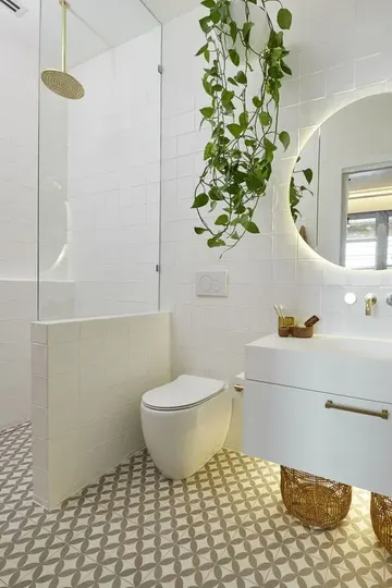 Mozaik fayanslı modern banyo, asma lavabo, duşu ayıran camlı alçak duvar ve saksı bitkisi.
