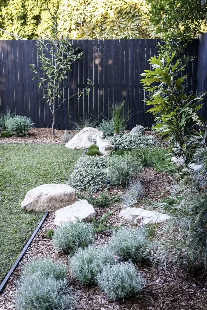Çim alan, kaya, çim ve çeşitli sade bitkiler içeren xeriscape ile tamamlanmış.