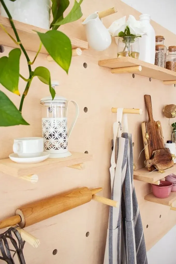 Büyük pegboard, farklı mutfak eşyalarını tutan çok sayıda raf ve kancaya sahip.