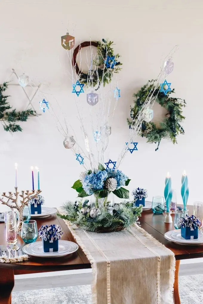 Gümüş ve mavi renklerin uyumu ile gümüş ve mavi mumlar, şık gümüş menorah ile etkileyici bir masa düzeni.
