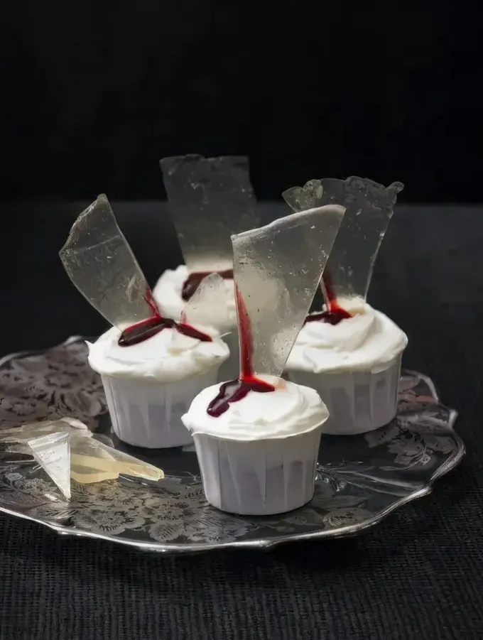 Kanlı cam parçalarıyla süslenmiş şık beyaz cupcakeler, Dexter temalı olsun olmasın her Cadılar Bayramı partisinde zarif durur.