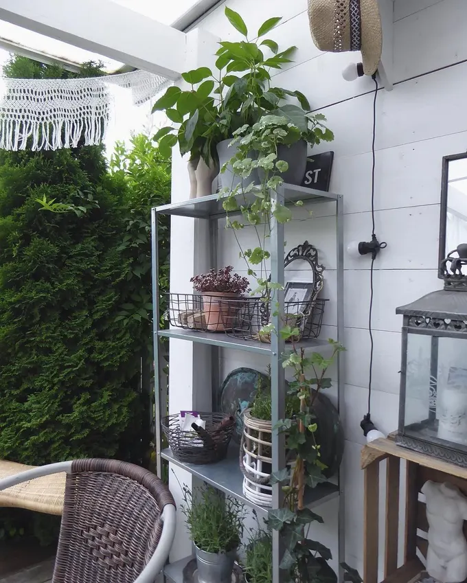 Galvanizli IKEA Hyllis, verandada saksı bitkileri ve sepetlerle dolu, doğayla uyumlu bir dış mekan köşesi oluşturmuş.