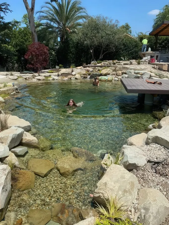 Çevresi taşlarla kaplı, üzerinde sadece ahşap güvertesi olan, doğal ve zamansız bir yüzme göleti.