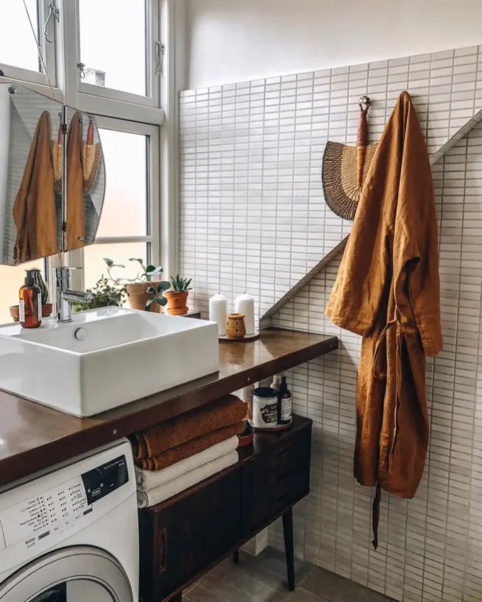 Ahşap tezgah altına yerleştirilmiş çamaşır makinesi, vintage tarzıyla uyumlu banyo dolabının içinde sıcak ve doğal bir ortam yaratıyor.
