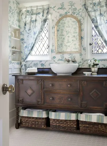 Nötr tonlarda, vintage koyu renkli lavabo dolabı, kuyu tipi lavabo, ayna ve çiçek desenli perdelerle şık misafir tuvaleti.