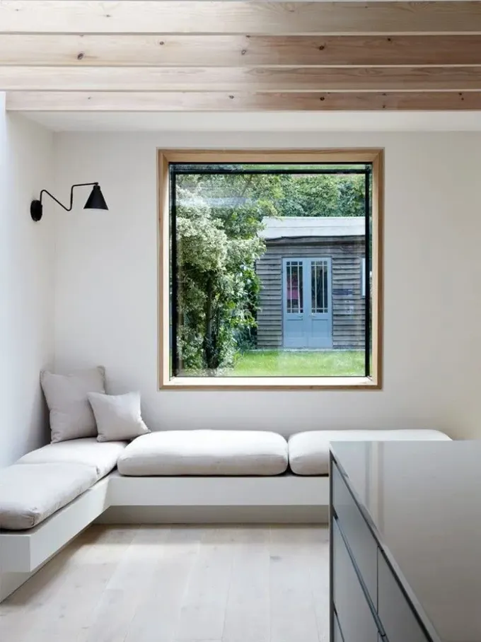 Minimalist oturma odası, oriel pencere ile içeriye yeşillik getirerek stilize edilmiştir.