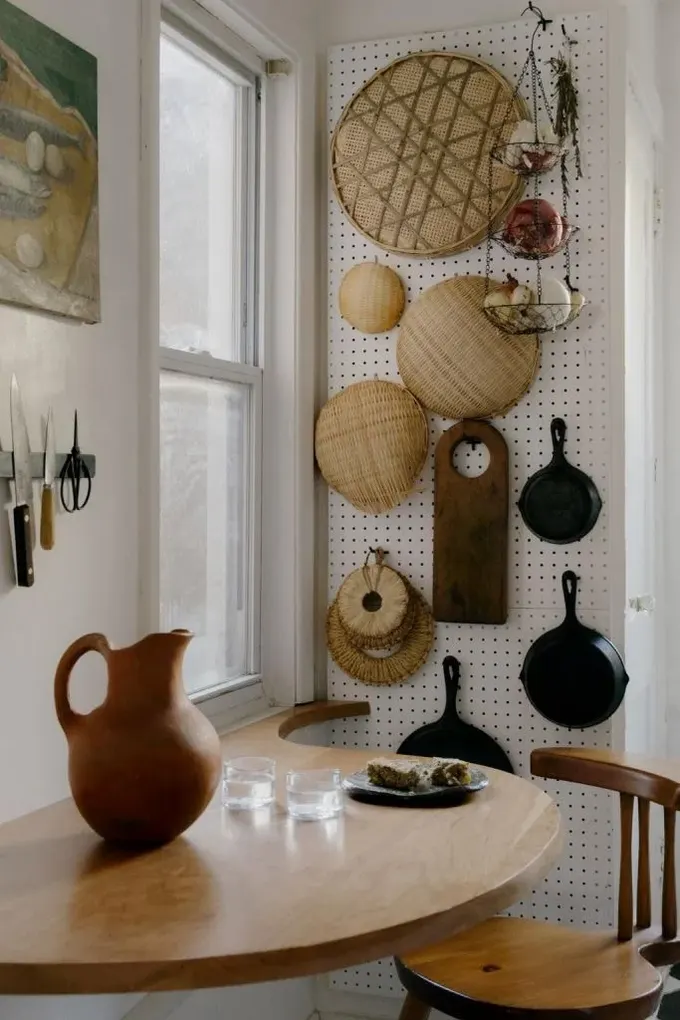 Dikey pegboard, kancalarla tamamlanmış ve tencere ile sepet koleksiyonunu tutuyor.