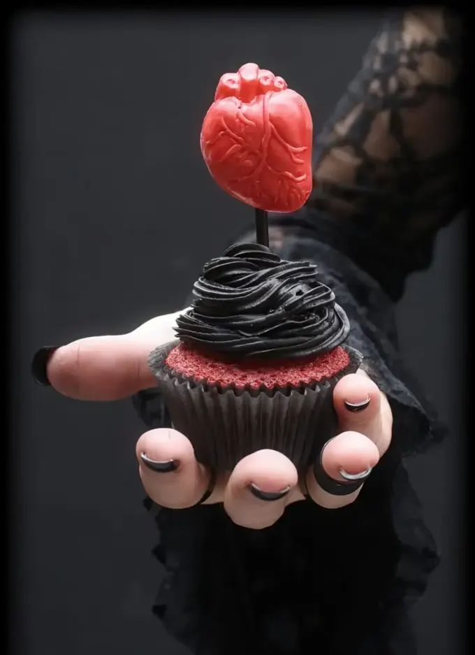 Üzerinde siyah çikolatalı kreması ve kırmızı kalp olan kırmızı kadife cupcake, inanılmaz çekici görünüyor.